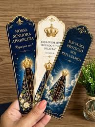 Marcadores católicos impressos segurados na mão sobre mesa de madeira